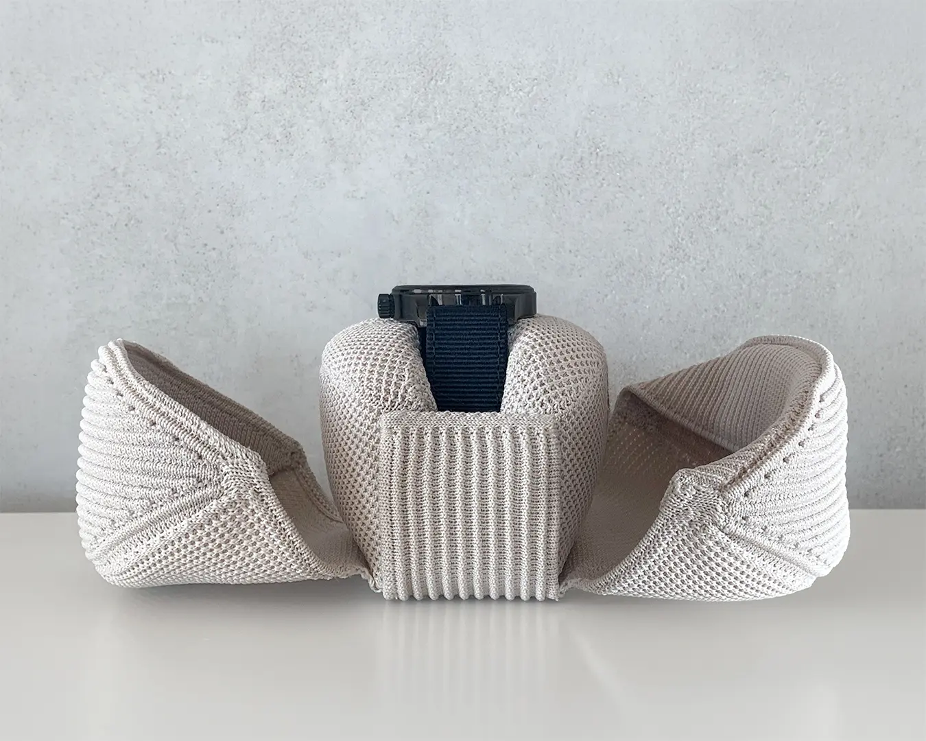 Open 3D knitted watch travel pouch holding a mechanical watch